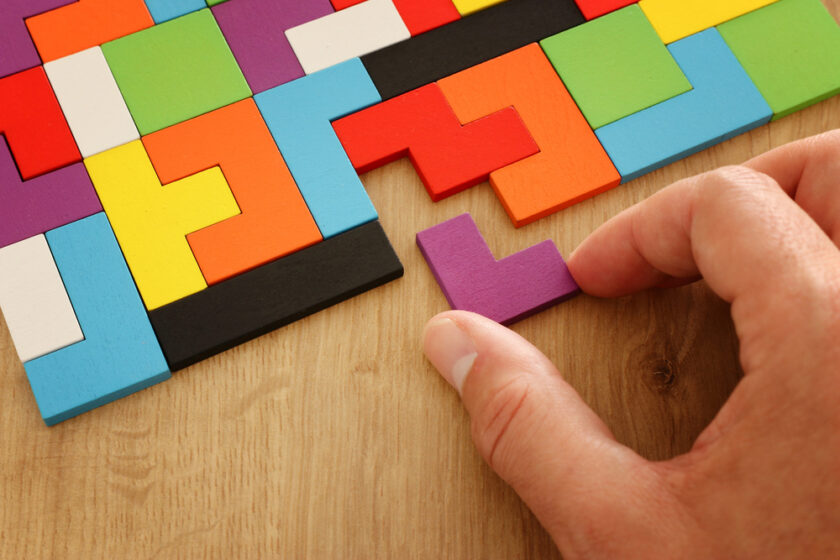 man putting the last piece into a colourful puzzle