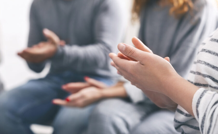 Group support. Patients clapping hands at psychotherapy session, close up
