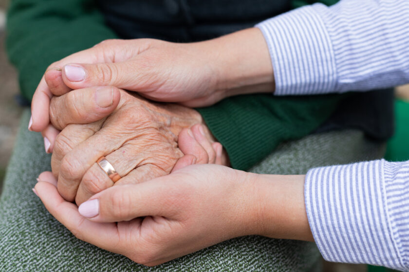 Close up picture of caregiver holding senior woman's wrinkled hands