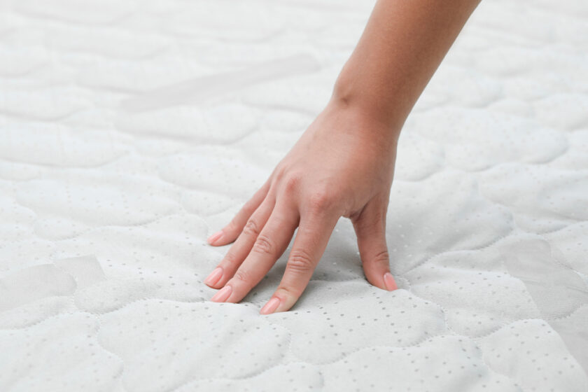 Woman touching new soft mattress, closeup view