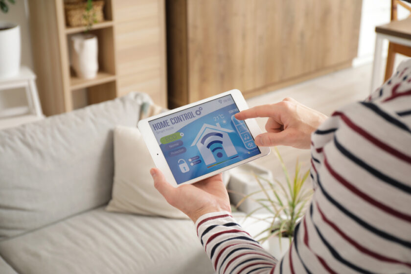 person holding a tablet with a smart home app on