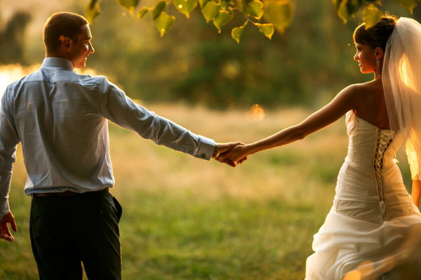 groom and bride is holding hands on the background green forest
