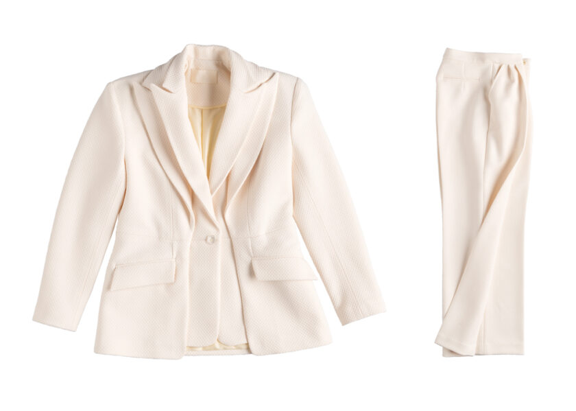 A cream-colored pantsuit is displayed on a white background. The set includes a fitted blazer with a single button and two front pockets, alongside straight-cut trousers. The fabric appears textured.