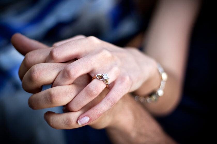 Close up of a young couples hands and diamond engagement ring with platinum and gold accents. Shallow depth of field.