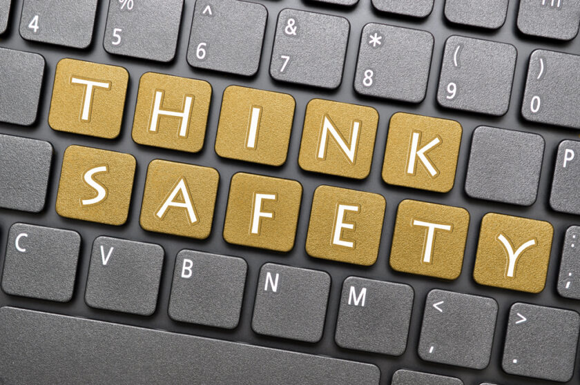 Computer keyboard with the words THINK SAFETY spelled out using gold-colored keys. The surrounding keys are gray.