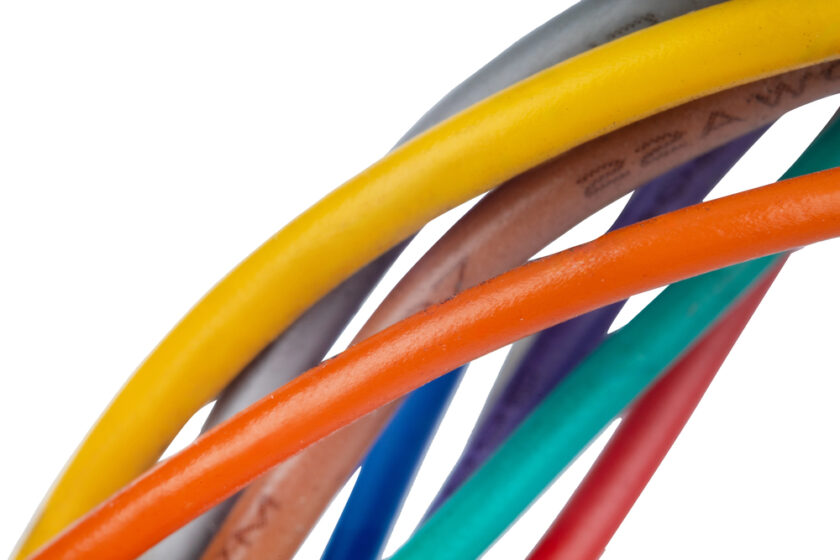 Close-up of several colorful electrical wires, including yellow, orange, green, blue, gray, and brown, twisted together against a white background.