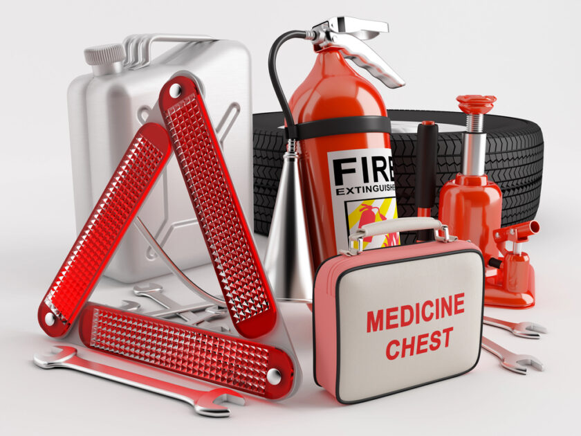 A collection of car emergency items, including a fire extinguisher, first aid medicine chest, reflective warning triangles, wrenches, a fuel can, a car jack, and a spare tire, arranged on a white background.