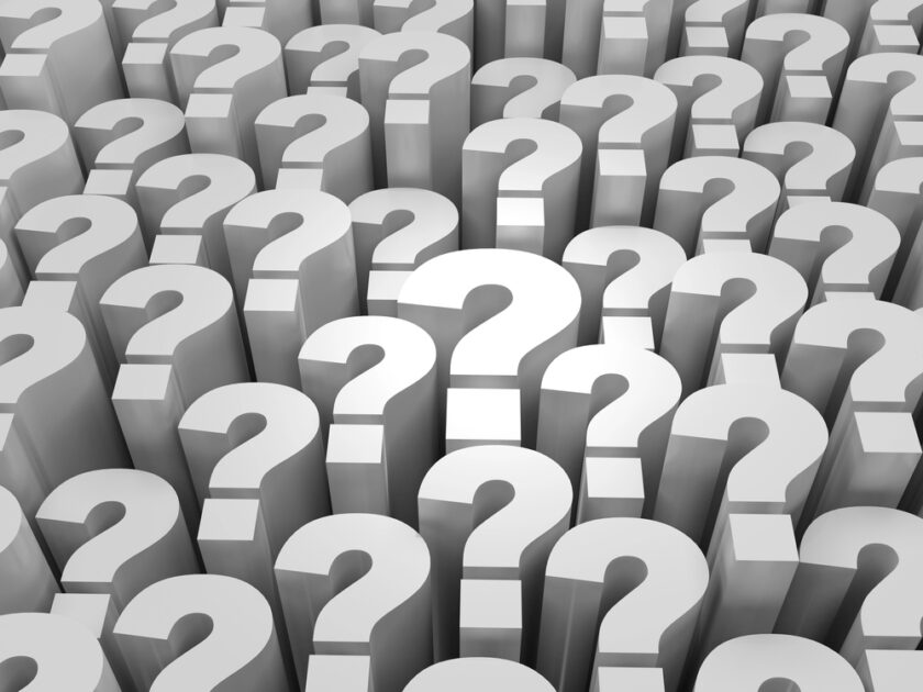 A repeating pattern of large, three-dimensional white question marks standing upright, with one question mark in the center highlighted by a bright light.