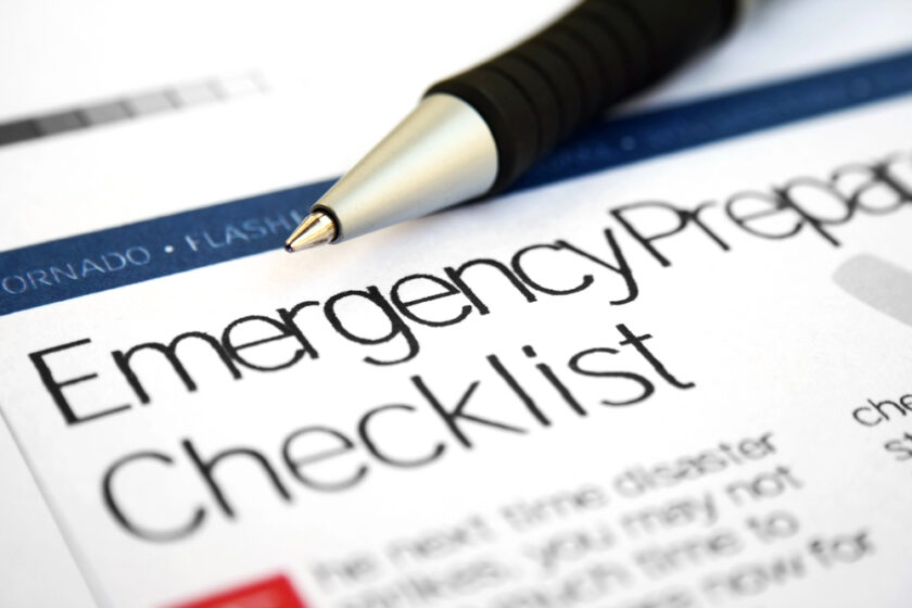 A close-up of a pen resting on a document titled Emergency Preparedness Checklist, with blurred text and part of the word TORNADO visible at the top.