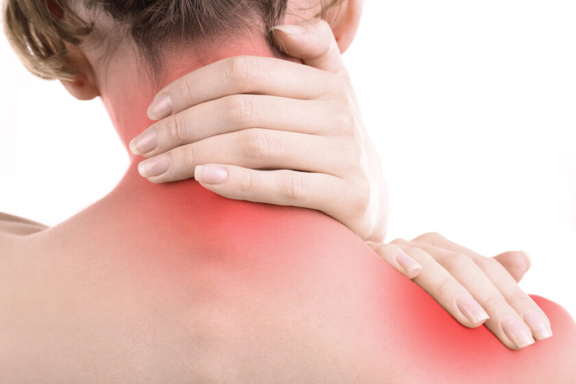 A person holding the back of their neck and shoulder, which are highlighted with a red area indicating pain or discomfort. The background is white.