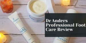 A flat lay of Dr Anders foot care products, including a nail treatment tube and a therapy cream jar, arranged on a white wooden surface with glowing salt lamps. Text overlay: Dr Anders Professional Foot Care Review.