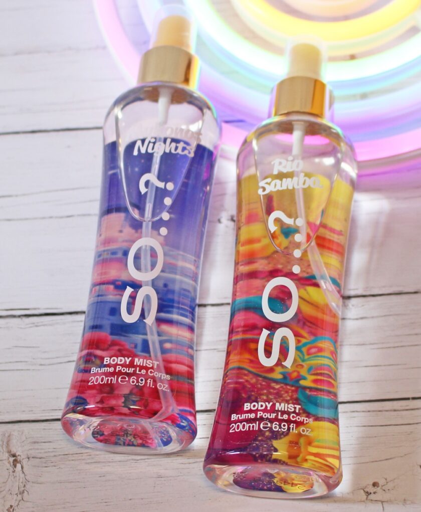 Two bottles of SO...? body mist, labelled Pink Nights and Rio Samba, are placed on a white wooden surface with a colourful, circular light in the background. Each bottle contains 200ml (6.9 fl. oz.).
