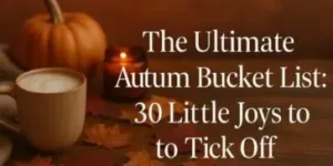 A cup of coffee, autumn leaves, a candle, and a pumpkin sit on a wooden surface. Text reads: The Ultimate Autumn Bucket List: 30 Little Joys to Tick Off.