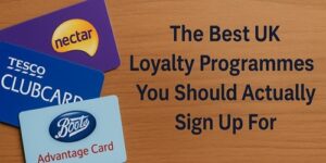 Three loyalty cards (Nectar, Tesco Clubcard, and Boots Advantage Card) are displayed on a wooden surface next to text reading, The Best UK Loyalty Programmes You Should Actually Sign Up For.