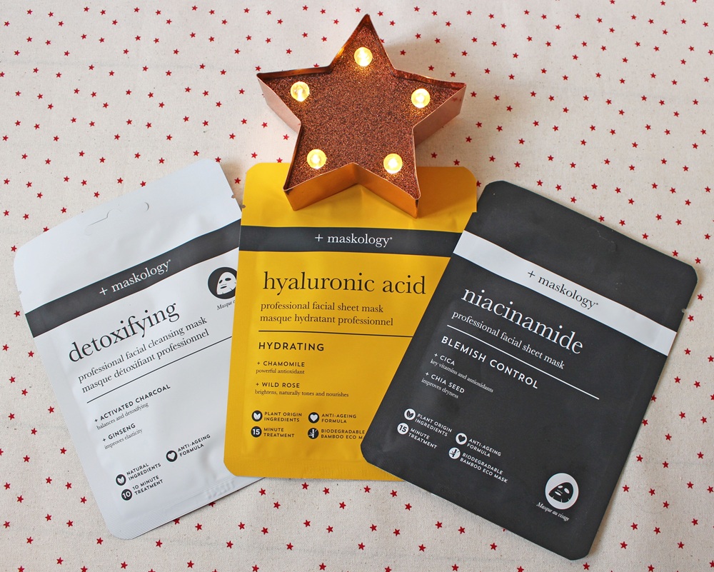 Three facial sheet mask packets labelled detoxifying, hyaluronic acid, and niacinamide are displayed on a star-patterned surface, with a lit decorative star above them.