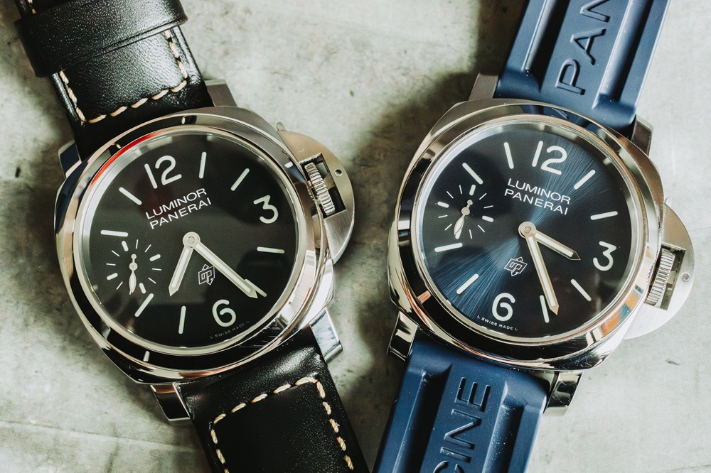 Two Panerai Luminor watches side by side: one with a black leather strap and black dial, and the other with a blue rubber strap and blue dial, both featuring large numerals and silver cases.