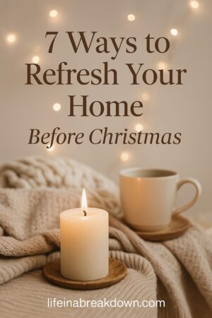 A lit candle and a mug on wooden coasters rest on a cosy blanket, with warm fairy lights in the background. Text reads: 7 Ways to Refresh Your Home Before Christmas. lifeinabreakdown.com.