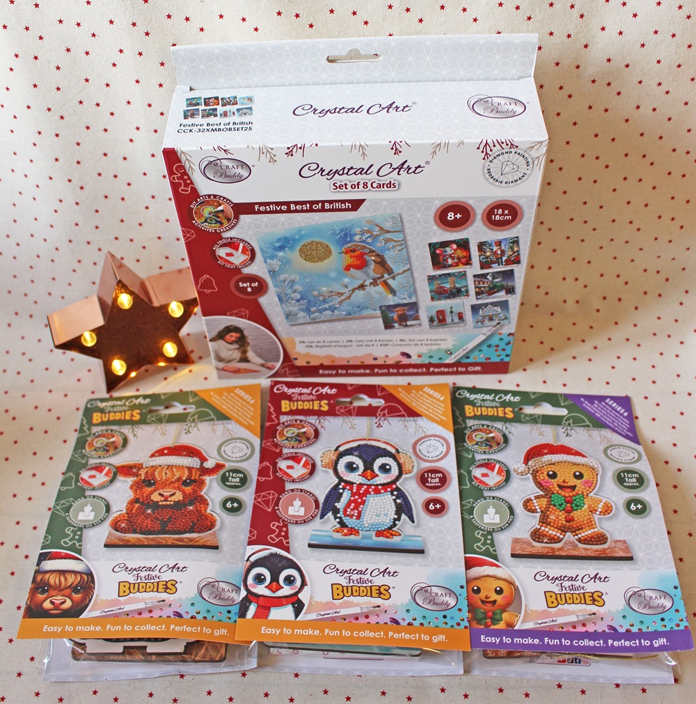 A set of festive Crystal Art kits, including greeting cards and three animal-themed craft packs (lion, penguin, bear), displayed on a polka dot surface with a small wooden star light.