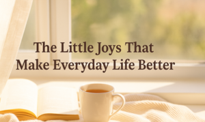 A sunlit window with a cup of tea, an open book, and a cosy blanket. Text in the centre reads: The Little Joys That Make Everyday Life Better. The background is softly blurred greenery.
