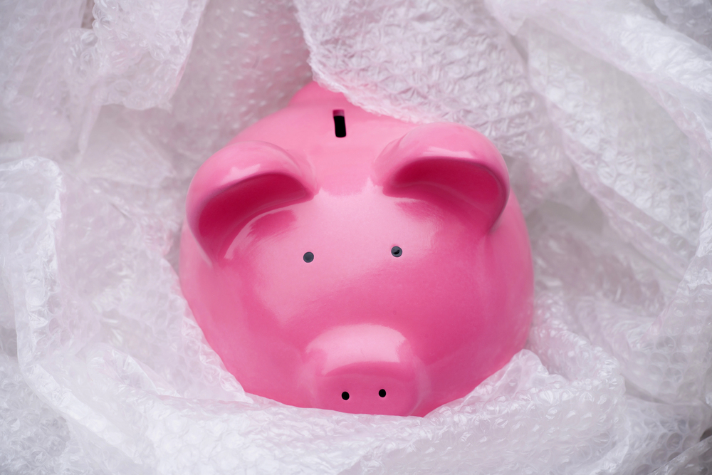 A pink piggy bank surrounded by sheets of clear bubble wrap.