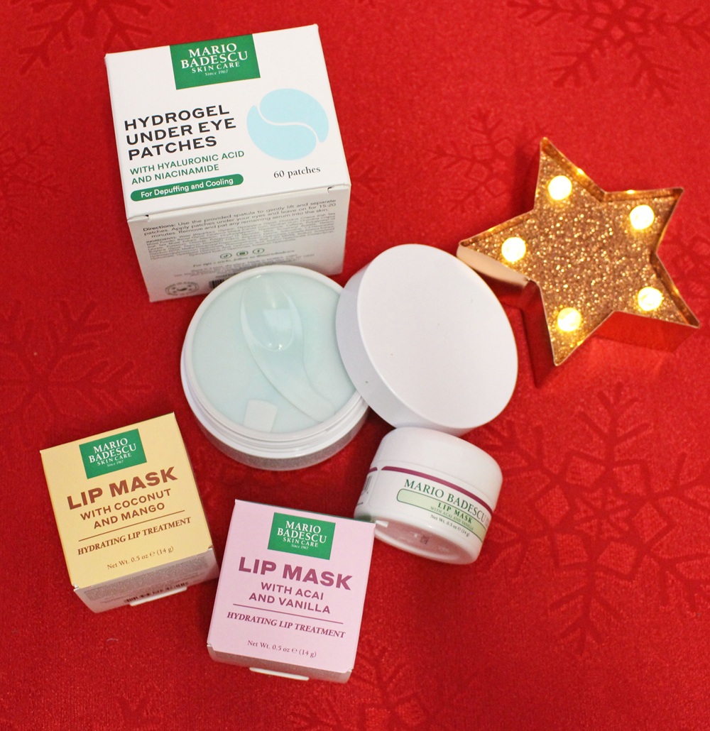 Skincare products from Mario Badescu, including Hydrogel Under Eye Patches and two types of Lip Mask, displayed on a red background with a lit star-shaped decoration.