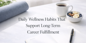 A notebook, pen, bowl of fruit, cup of coffee, and rolled yoga mat on a table with the text Daily Wellness Habits That Support Long-Term Career Fulfilment displayed in the centre.
