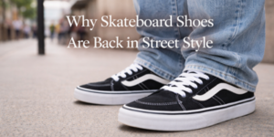 Person in blue jeans wearing black-and-white skateboard trainers stands on a city pavement. White text reads: Why Skateboard Trainers Are Back in Street Style. Background shows a blurred urban scene.