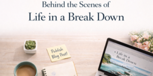 A workspace with a laptop displaying Life in a Break Down, a coffee cup, a notebook, a sticky note reading Publish Blog Post!, a small plant, and pink flowers on a light wood desk.