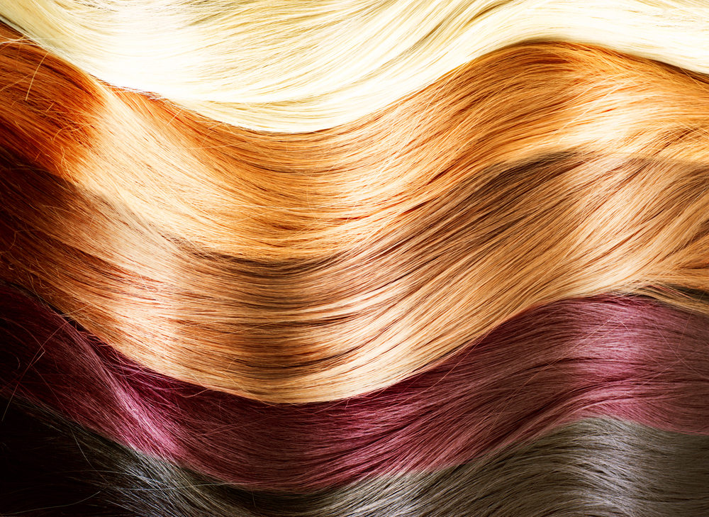 Several sections of hair in different colours, including shades of blonde, orange, brown, red, and grey, are arranged in horizontal waves, creating a layered and textured pattern.