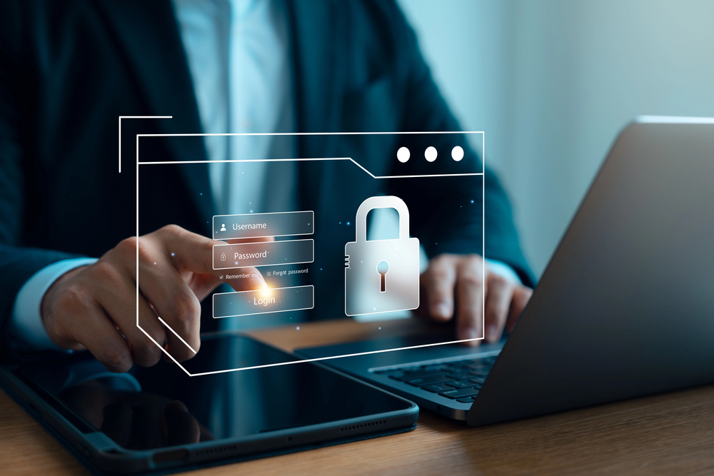 A person in a suit using a laptop, with a virtual log-in interface and a large padlock icon symbolising cyber security and data protection displayed in the foreground.