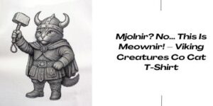 A drawing of a cat dressed as a Viking, wearing a horned helmet and armour, holding a hammer. Next to it, text reads: Mjolnir? No... This Is Meownir! — Viking Creatures Co Cat T-Shirt.