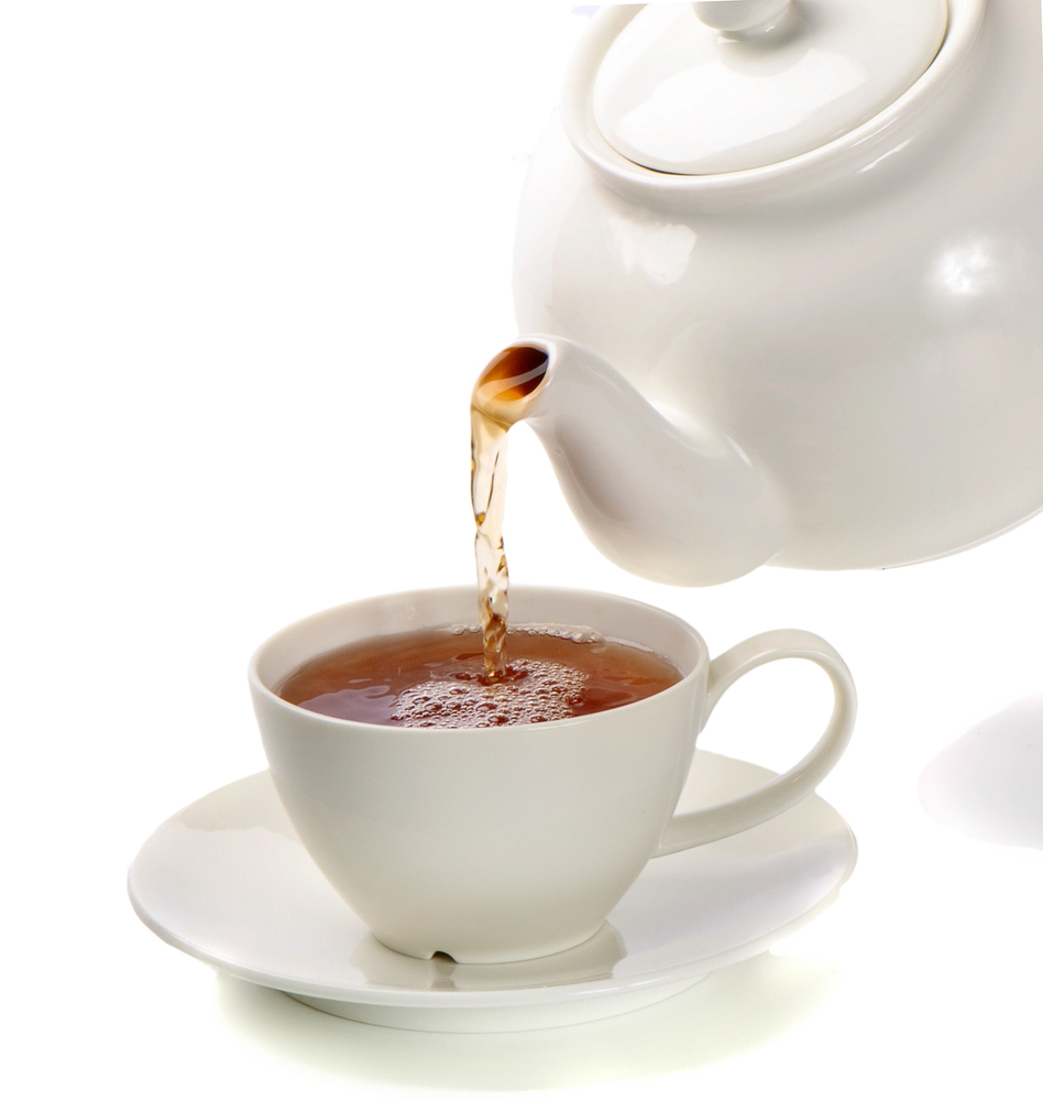 A white teapot pouring hot tea into a matching white teacup and saucer, set against a plain white background.