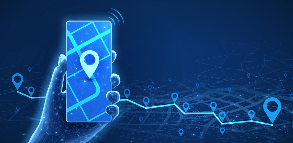 A digital illustration of a hand holding a mobile phone with a glowing map and location pin icons, representing navigation and GPS tracking technology on a blue background.