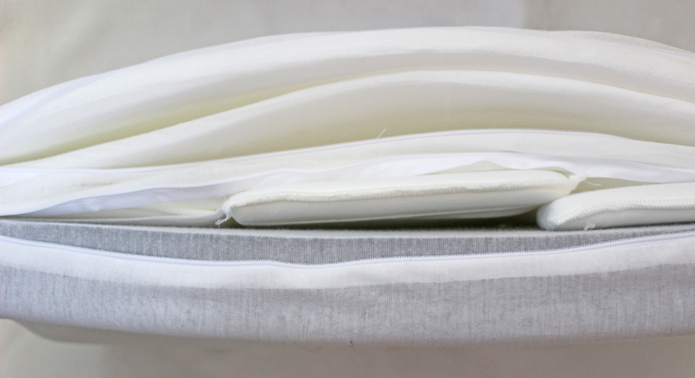 A close-up view of several neatly folded white and light grey fabrics stacked on top of each other.