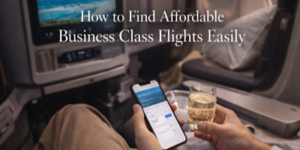 Person sitting in a business class aeroplane seat, holding a mobile displaying a flight search and a glass of drink, with the text How to Find Affordable Business Class Flights Easily overlaid on the image.