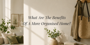 A cosy, sunlit room with neutral tones, plants, a coat and woven bag hanging on hooks, and the text What Are The Benefits Of A More Organised Home? displayed on the wall.