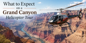 A helicopter flies over the Grand Canyon with deep red rock formations. Text reads: What to Expect on a Grand Canyon Helicopter Tour. The sky is clear with scattered clouds.