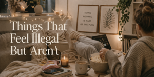 A person in cosy clothes relaxes on a sofa with popcorn, candles, snacks, and a hot drink. The room is warmly lit with fairy lights and plants, and a sign reads, DOING NOTHING IS PART OF THE PLAN. Text: Things That Feel Illegal But Aren’t.