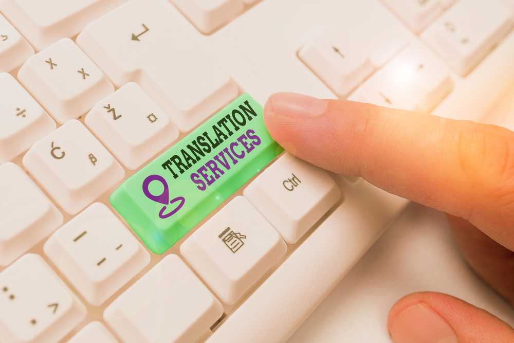 A finger presses a green key labelled Translation Services on a white computer keyboard.
