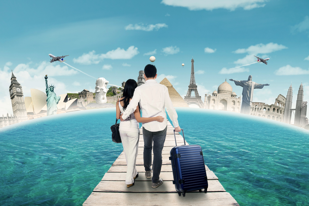 A couple walks on a pier over water, holding each other and a suitcase, with famous landmarks like the Eiffel Tower, Statue of Liberty, and Taj Mahal in the background, representing world travel.