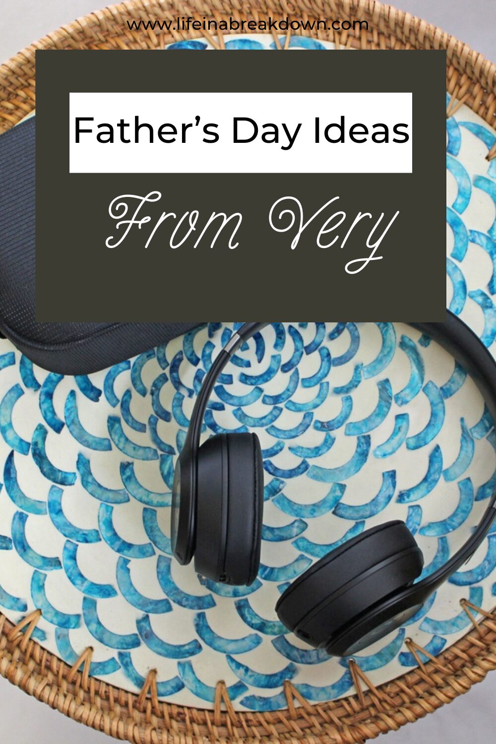 A pair of black wireless headphones and their case sit on a round wicker tray with a blue and white patterned plate. Overlaid text reads: Father’s Day Ideas From Very.