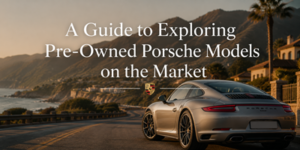 A silver Porsche sports car drives along a coastal motorway at sunset, with mountains and the sea in the background. Text reads: A Guide to Exploring Pre-Owned Porsche Models on the Market.
