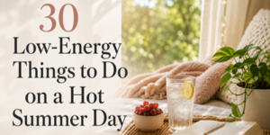 Text reads, 30 Low-Energy Things to Do on a Hot Summer Day. Next to the text is a cosy window nook with a blanket, a glass of iced water with lemon, a bowl of grapes, and a potted plant in sunlight.