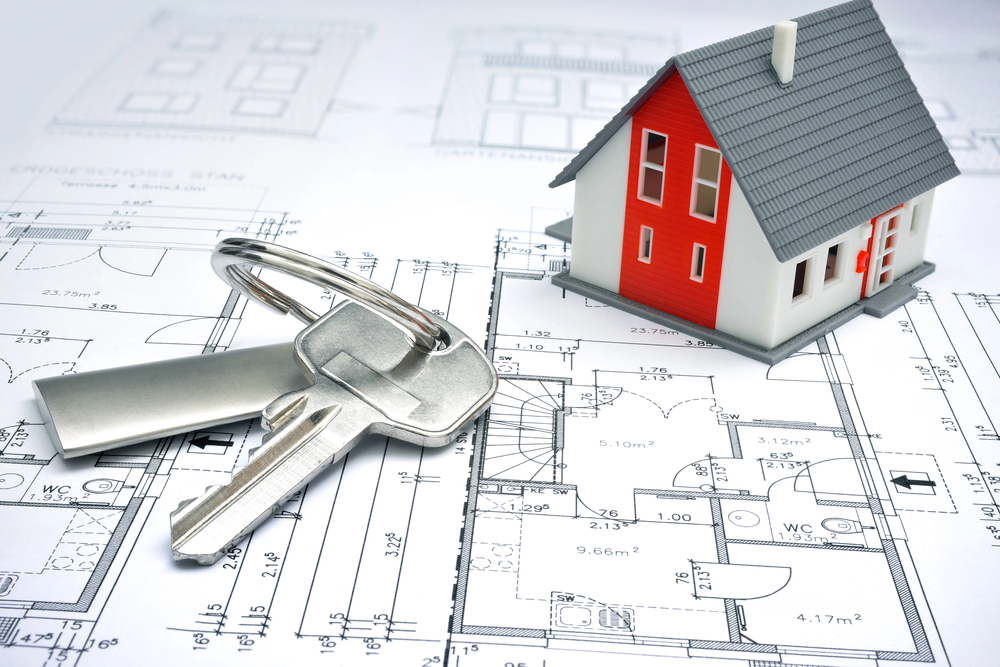 A set of house keys and a small model house rest on architectural floor plans, symbolising property, home ownership, or property investment.