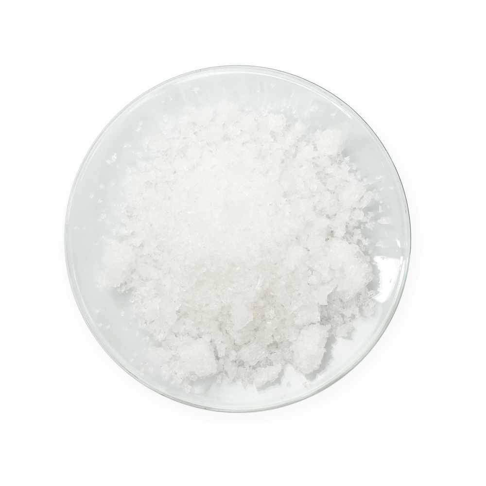 A clear glass bowl filled with coarse, flaky white sea salt, viewed from above on a white background.