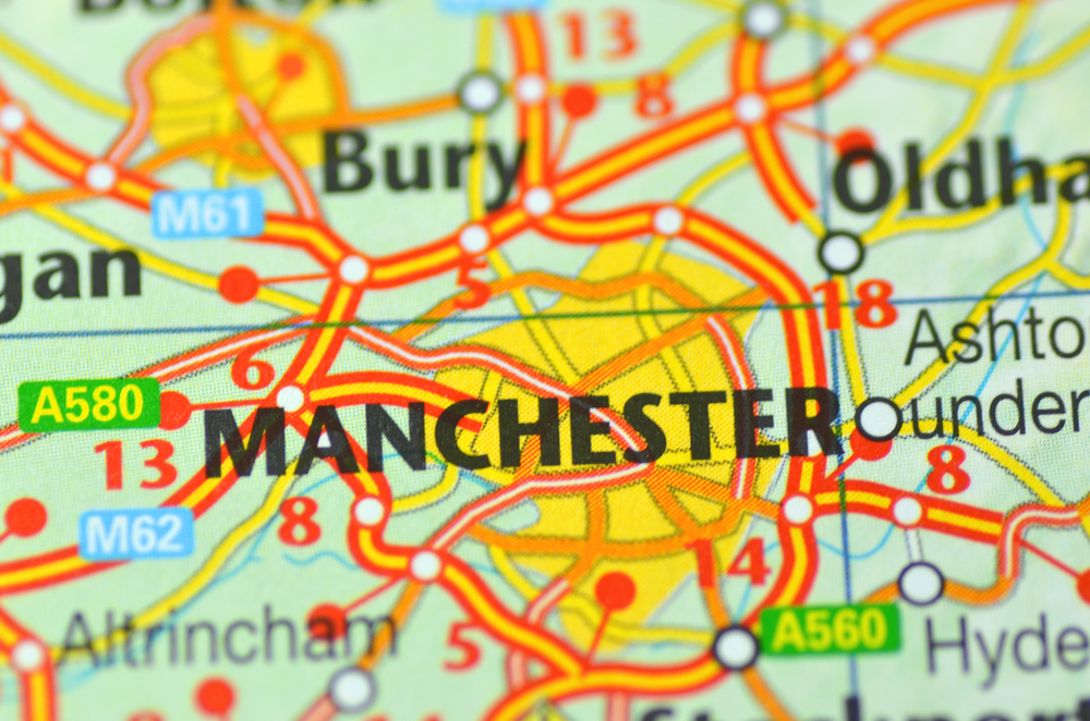 Close-up of a colourful road map showing Manchester and surrounding areas, including Bury and Oldham, with road numbers and highlighted routes.