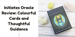 A boxed set of Initiates Oracle cards sits on a white wooden surface with three crystals beside it. The text beside the image reads: Initiates Oracle Review: Colourful Cards and Thoughtful Guidance.