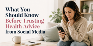 A woman sits on a sofa, looking thoughtfully at her mobile. Text on the image reads, What You Should Know Before Trusting Health Advice from Social Media. A cup, notebook, and pen are on the table in front of her.