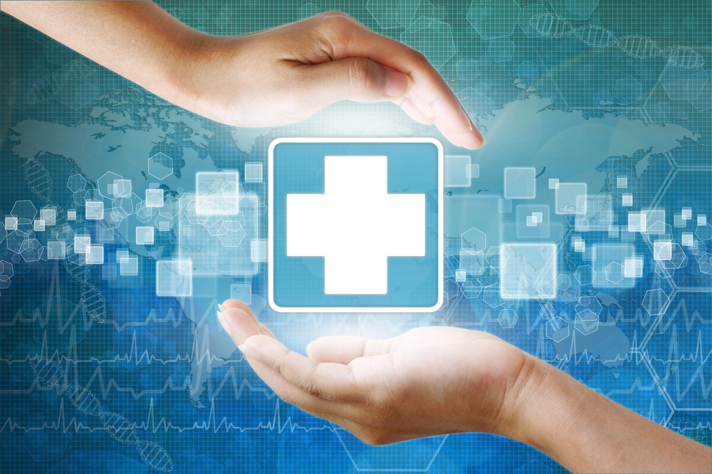 Two hands encircle a glowing medical cross icon, symbolising healthcare protection, with a digital world map and health data graphics in the background.