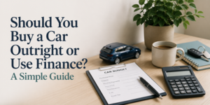 A desk with a car budget form, calculator, pen, coffee cup, car keys, a small toy car, and a plant. Text reads: “Should You Buy a Car Outright or Use Finance? A Simple Guide.”.